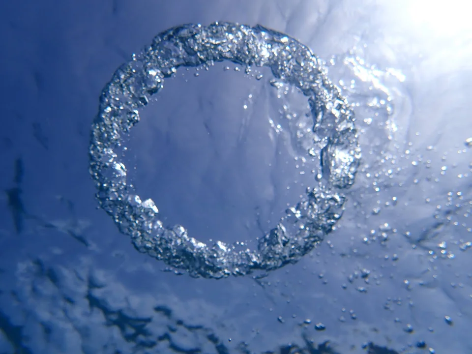 Burbuja circular bajo el agua iluminada por el sol